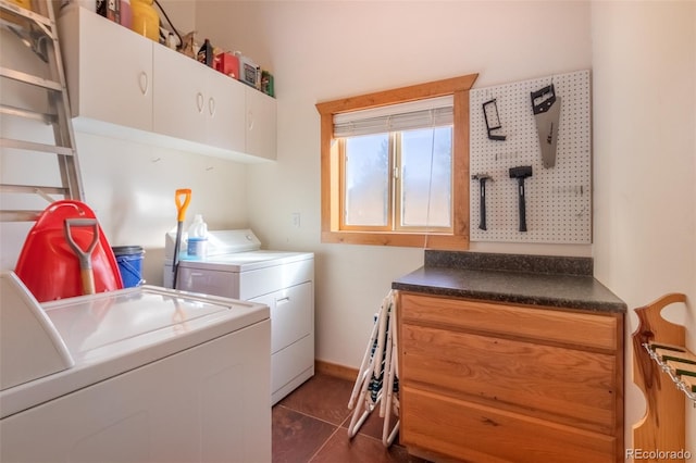 laundry area with separate washer and dryer, dark tile patterned flooring, and cabinets