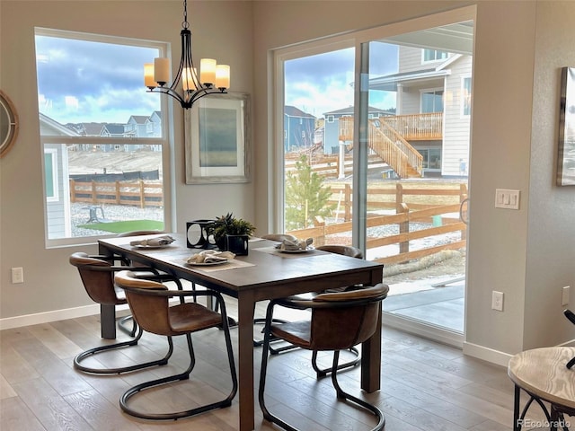 dining space with a healthy amount of sunlight, light hardwood / wood-style floors, and a chandelier
