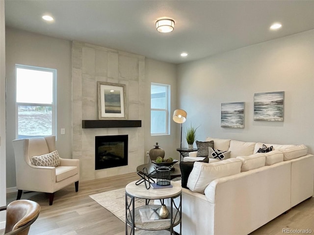 living room featuring a tile fireplace and light hardwood / wood-style flooring
