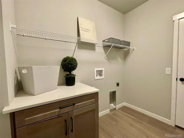 laundry room with electric dryer hookup, hookup for a washing machine, light hardwood / wood-style flooring, and cabinets
