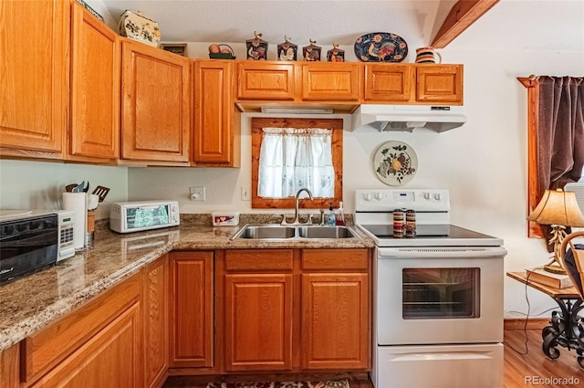 kitchen with a sink, wood finished floors, light stone counters, under cabinet range hood, and electric stove