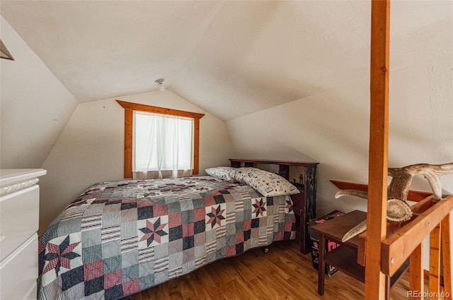 bedroom with lofted ceiling and wood finished floors
