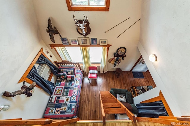 living area with wood finished floors, a wealth of natural light, and a towering ceiling