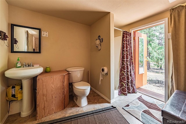 full bathroom featuring toilet, a shower with curtain, and baseboards