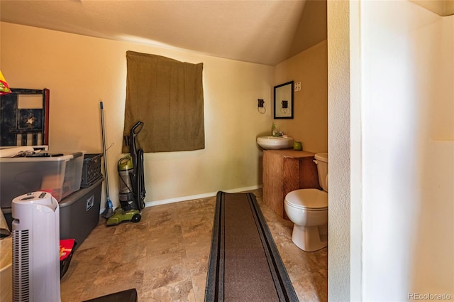 interior space featuring vaulted ceiling, a sink, and stone finish flooring