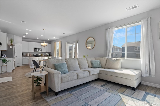 living area with visible vents, plenty of natural light, and wood finished floors