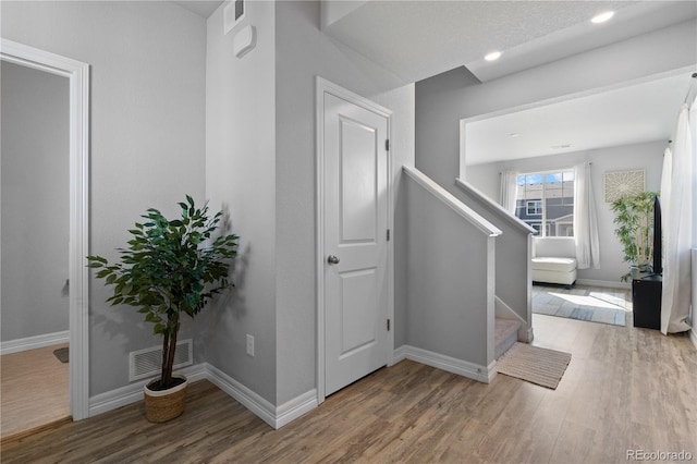 hallway featuring stairs, wood finished floors, visible vents, and baseboards