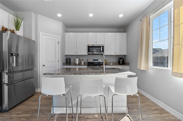 kitchen featuring dark wood finished floors, stone countertops, a sink, stainless steel appliances, and white cabinets