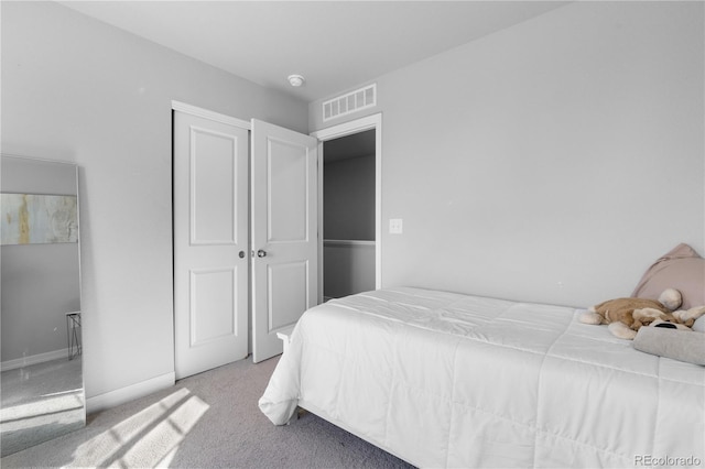 carpeted bedroom with visible vents, baseboards, and a closet