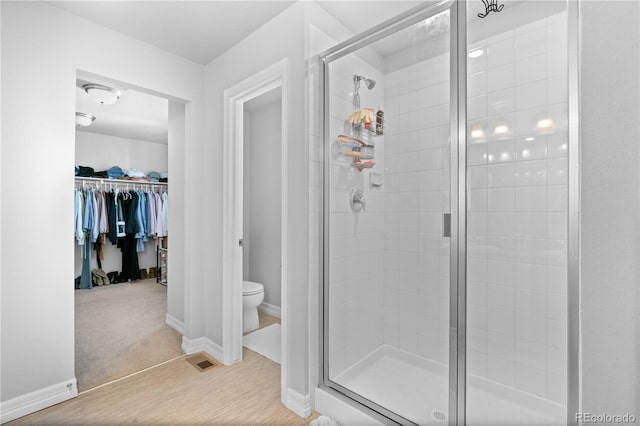 full bathroom featuring visible vents, toilet, a stall shower, wood finished floors, and baseboards