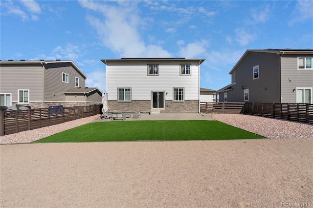 back of property featuring a patio area, stone siding, a lawn, and a fenced backyard