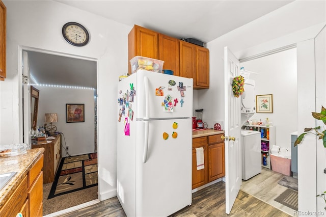 609 W 8th St Unit 611, Pueblo, CO 81003 - kitchen with freestanding refrigerator, stacked washing machine and dryer, light wood-style flooring, light countertops, and brown cabinets