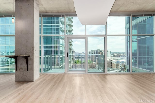 1700 Bassett St Unit 1102, Denver, CO 80202 - unfurnished living room with expansive windows, wood finished floors, a city view, and healthy amount of natural light