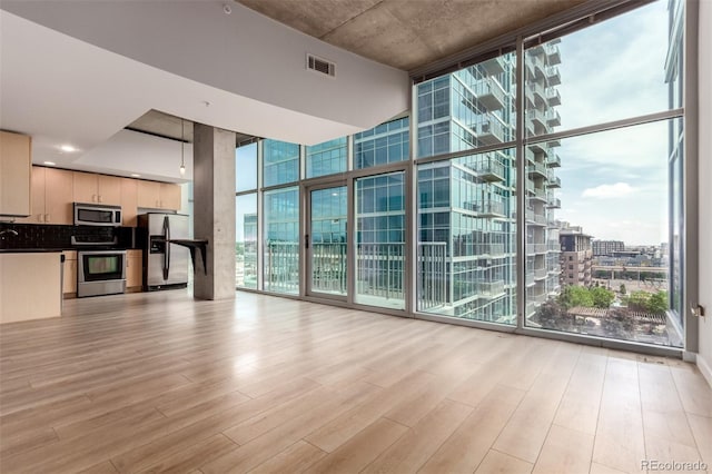 1700 Bassett St Unit 1102, Denver, CO 80202 - unfurnished living room featuring a wall of windows, light wood-style flooring, and a city view