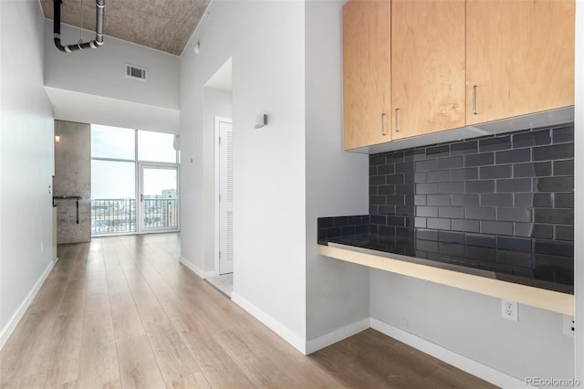 1700 Bassett St Unit 1102, Denver, CO 80202 - kitchen featuring wood finished floors, dark countertops, decorative backsplash, and baseboards