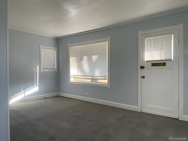 empty room featuring dark colored carpet and baseboards