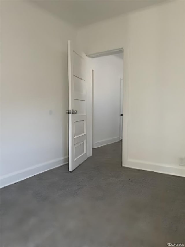 spare room featuring finished concrete floors and baseboards