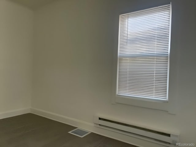 unfurnished room with baseboard heating, visible vents, and baseboards