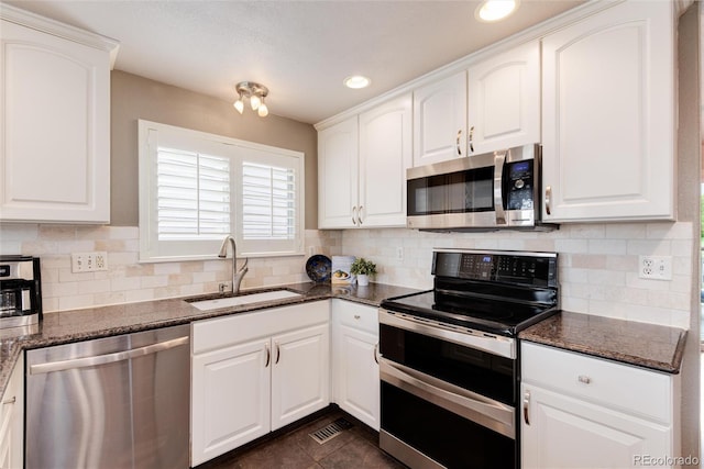 kitchen featuring stainless steel appliances, a sink, backsplash, dark stone countertops, and recessed lighting