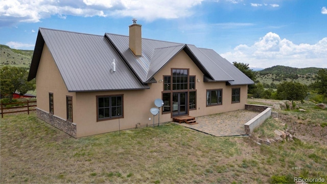 rear view of house with a mountain view, a patio area, and a lawn