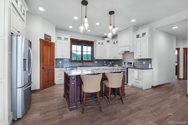 kitchen featuring white cabinets, stainless steel appliances, a kitchen island, and pendant lighting