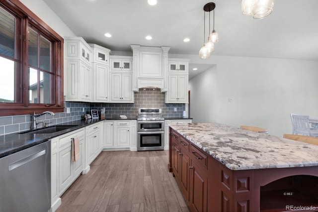 kitchen featuring white cabinets, stainless steel appliances, hanging light fixtures, and tasteful backsplash