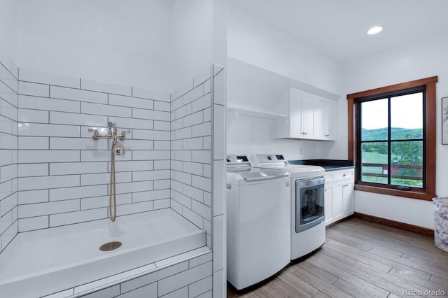 laundry area with independent washer and dryer, cabinets, and light hardwood / wood-style flooring