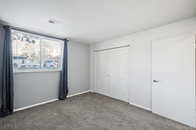 unfurnished bedroom with a closet and dark colored carpet