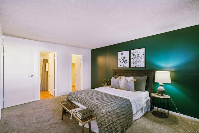 carpeted bedroom featuring ensuite bathroom and a textured ceiling