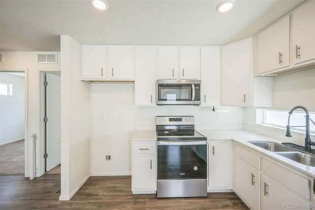 18211 E 51st Ave, Denver, CO 80249 - kitchen with stainless steel appliances, a sink, light countertops, white cabinetry, and dark wood-type flooring