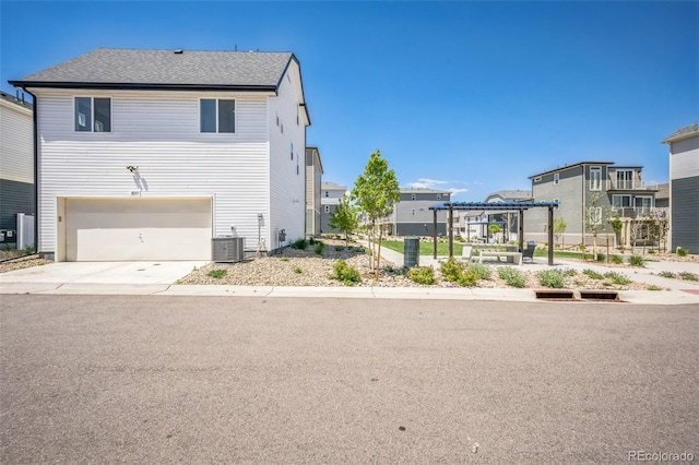 18211 E 51st Ave, Denver, CO 80249 - view of side of property featuring an attached garage, a pergola, driveway, and cooling unit