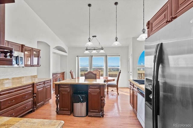 kitchen with a center island, light hardwood / wood-style floors, pendant lighting, lofted ceiling, and appliances with stainless steel finishes