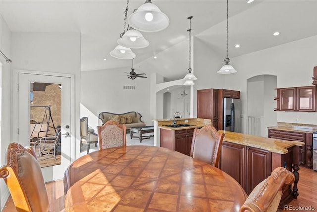 dining room featuring ceiling fan, sink, high vaulted ceiling, and wood-type flooring