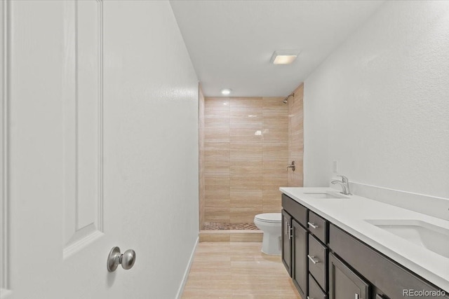 bathroom with vanity, toilet, and a tile shower