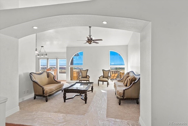 living room with ceiling fan with notable chandelier and lofted ceiling