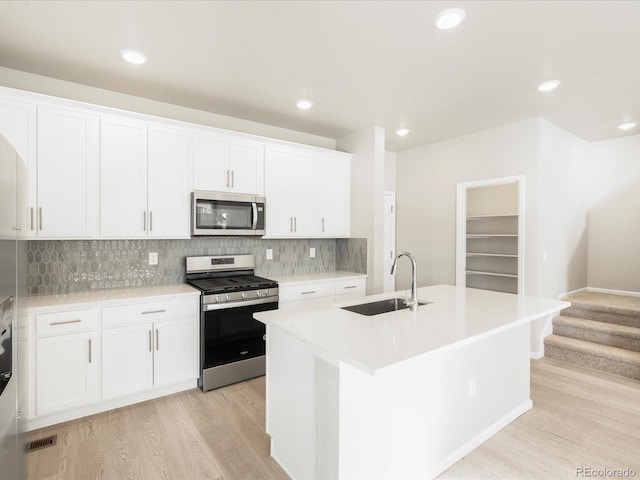 kitchen with appliances with stainless steel finishes, sink, a center island with sink, and white cabinets