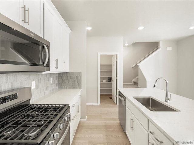 kitchen with sink, white cabinets, decorative backsplash, light stone counters, and stainless steel appliances