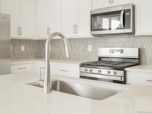 kitchen featuring white cabinetry, decorative backsplash, stainless steel appliances, and light stone counters