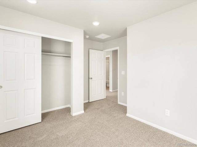 unfurnished bedroom featuring light colored carpet and a closet