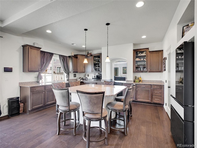 19155 Robins Dr, Denver, CO 80249 - kitchen featuring a kitchen island, dark wood finished floors, arched walkways, a kitchen breakfast bar, and fridge