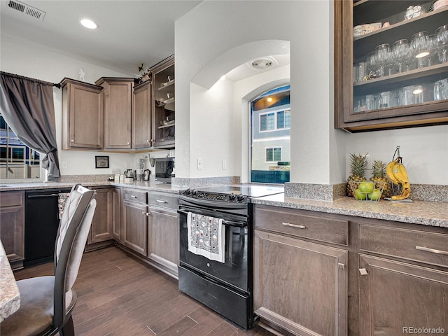 19155 Robins Dr, Denver, CO 80249 - kitchen featuring black appliances, arched walkways, dark wood-style floors, glass insert cabinets, and light stone countertops