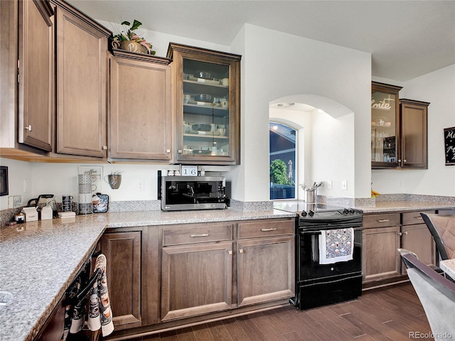 19155 Robins Dr, Denver, CO 80249 - kitchen featuring black / electric stove, stainless steel microwave, dark wood finished floors, arched walkways, and light stone countertops