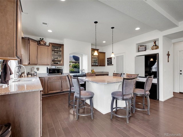 19155 Robins Dr, Denver, CO 80249 - kitchen with stainless steel microwave, a breakfast bar, dark wood finished floors, and recessed lighting