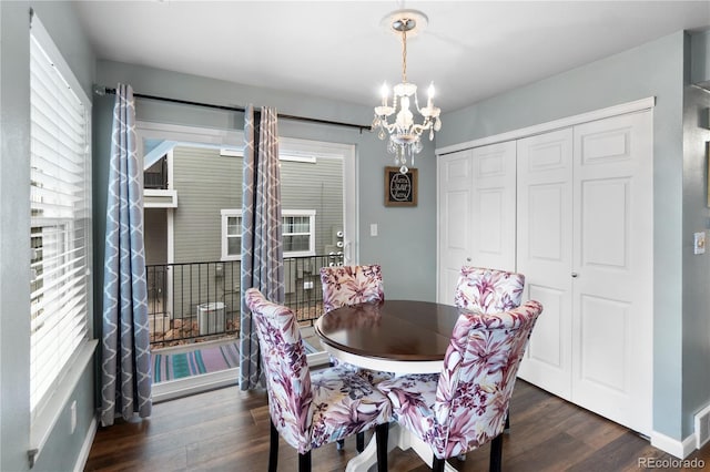 dining space with dark hardwood / wood-style flooring, an inviting chandelier, and a wealth of natural light