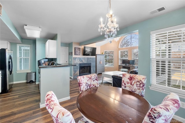 dining space with dark hardwood / wood-style flooring, a notable chandelier, and a tiled fireplace