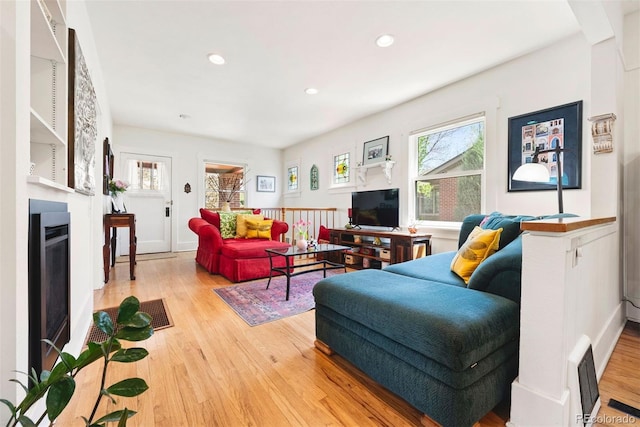 living area with visible vents, recessed lighting, light wood finished floors, and a fireplace with flush hearth