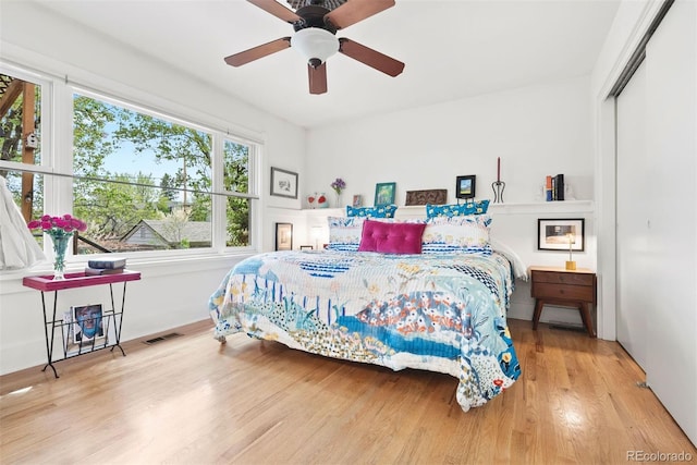 bedroom with a ceiling fan, a closet, wood finished floors, and visible vents