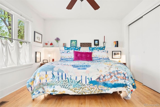 bedroom featuring a ceiling fan, a closet, wood finished floors, and visible vents