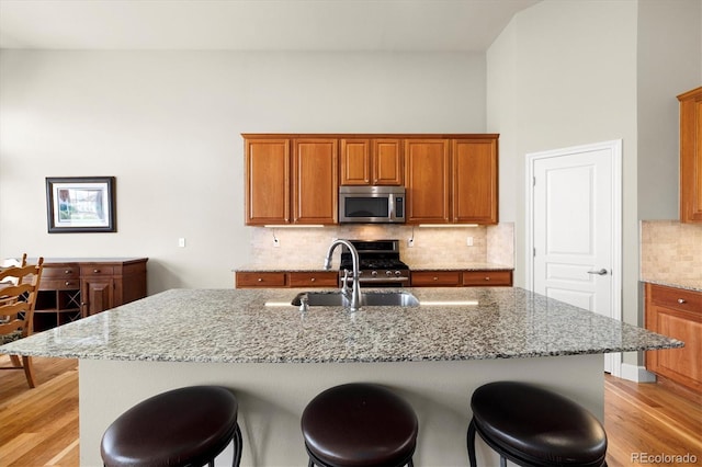 14443 W 88th Dr Unit B, Arvada, CO 80005 - kitchen featuring stainless steel appliances, light wood-type flooring, a breakfast bar area, brown cabinets, and light stone countertops