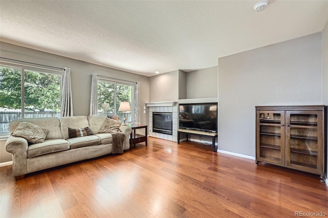 9890 Gaylord St, Thornton, CO 80229 - living area featuring wood finished floors, a textured ceiling, and a tiled fireplace